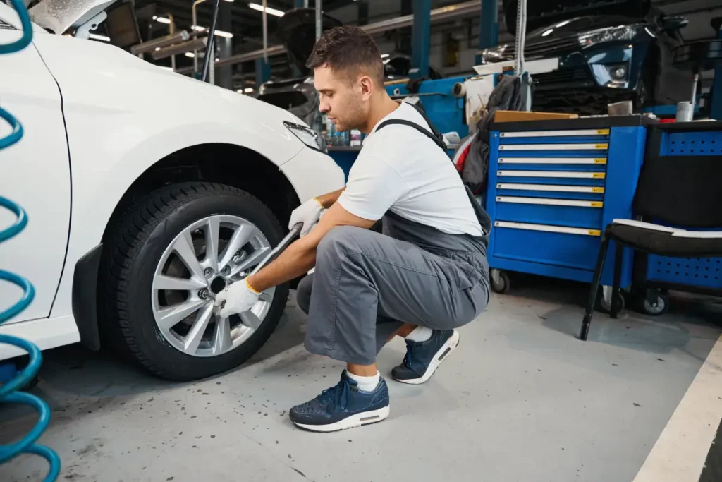 Kfz-Mechaniker wechselt einen Autoreifen in der Werkstatt.
